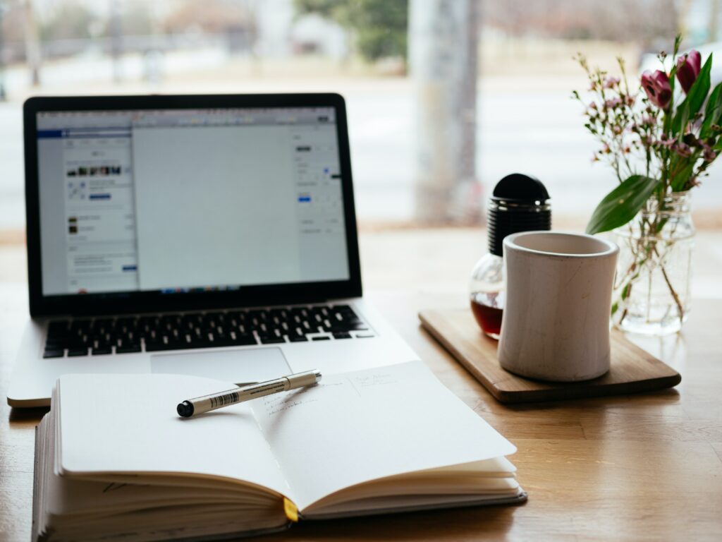 desk with a laptop open notebook and coffee mug