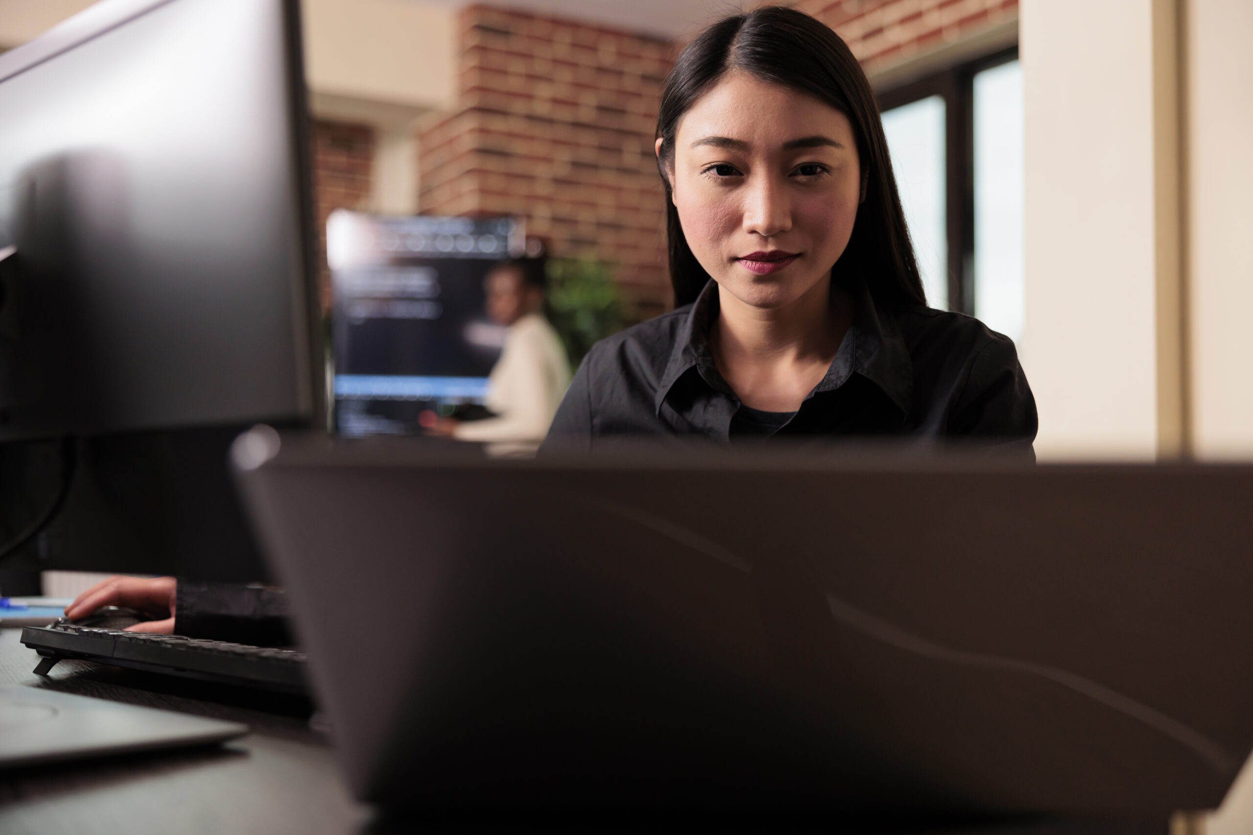Young woman looking at a laptop and desktop screen